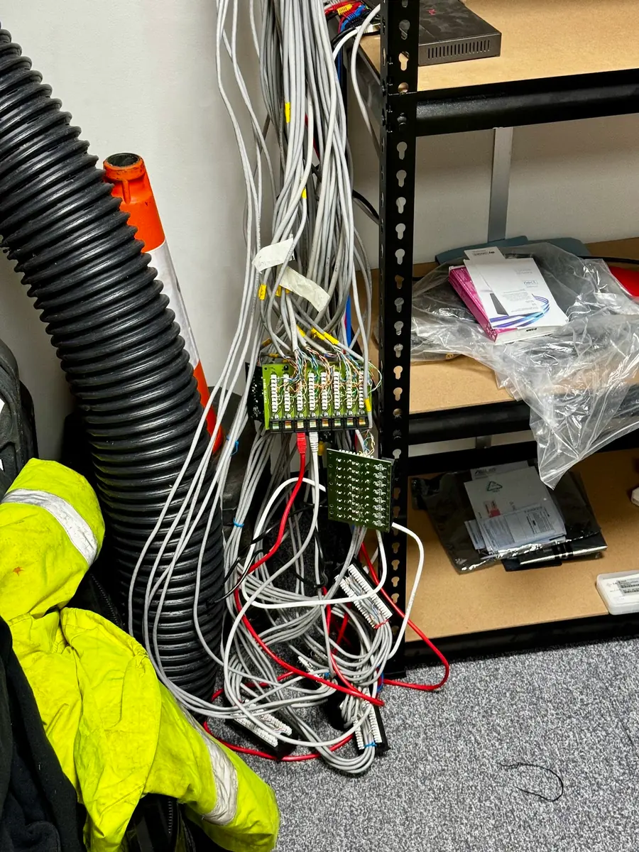 Before: unterminated network cabling hanging over open punch-down strips on storage shelving